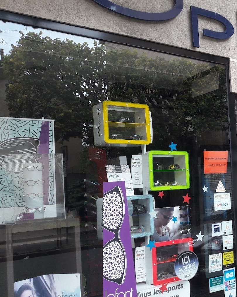La vitrine d’Optic Gorcy, avenue Paul Vaillant-Couturier : grand O bleu marine de l’enseigne, présentoirs de lunettes de sport et affiches Lafont